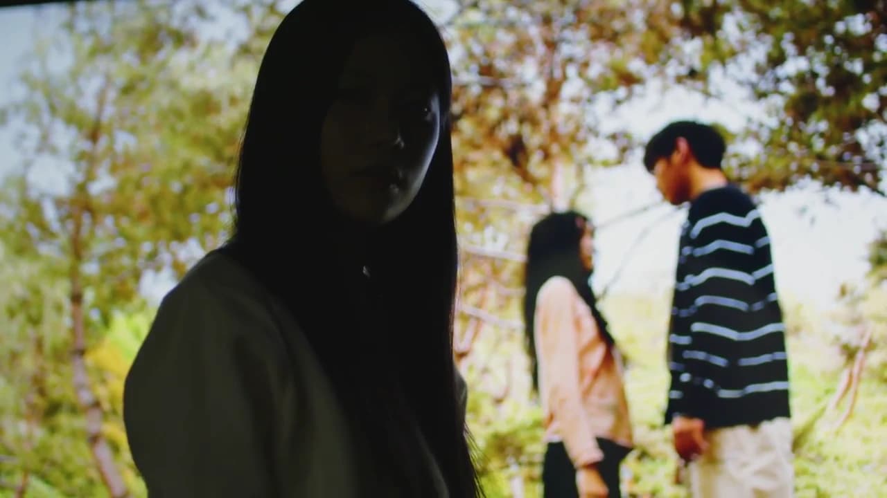 두 인물이 투사된 영상 앞에 여성이 서 있는 네가 이미 찾아버린 스틸